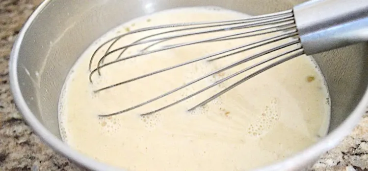 Step 4.1: Slowly whisk the hot milk into the eggs, a little at a time to prevent scrambling