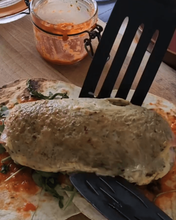 Step 3.1: Place one of the cheesy ham omelette rolls in the center of each tortilla and roll the tortilla around it tightly