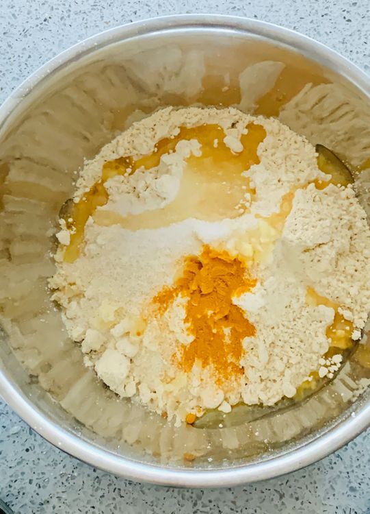 Step 1.1: Add gram flour (besan), semolina (suji), ginger, turmeric, sugar, salt, oil, and water to a mixing bowl