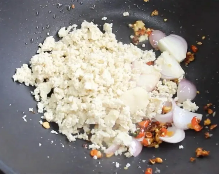 Step 2.1: Add the chopped onion and crumbled tofu to the wok