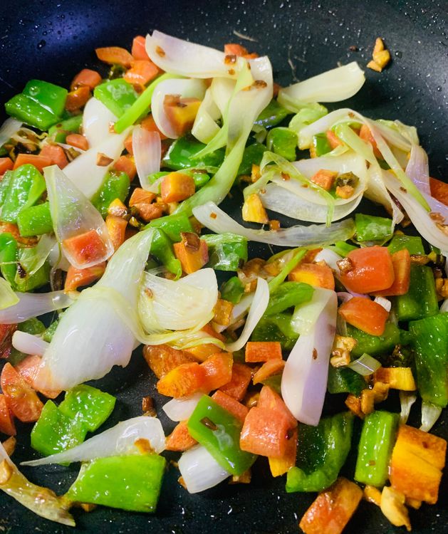 Step 2.1: Add the sliced onions, chopped carrots and capsicum and toss for 2-3 minutes