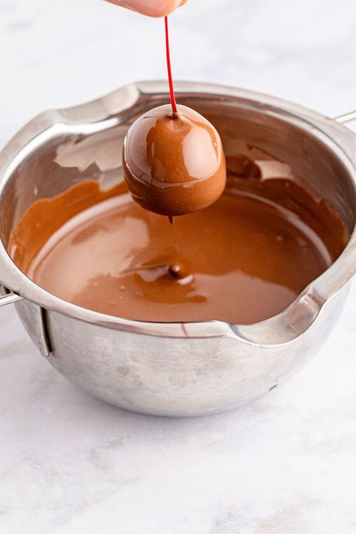 Step 2.1: Gently hold the cherry by the stem and dip it into the chocolate candy, one at a time