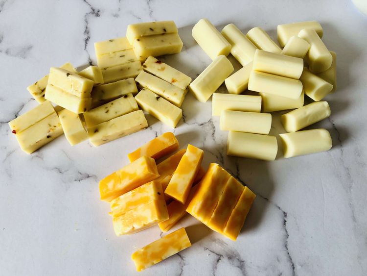 Step 1.1: Cut the cheddar, pepper jack, and string cheese sticks into 4 equal-sized pieces