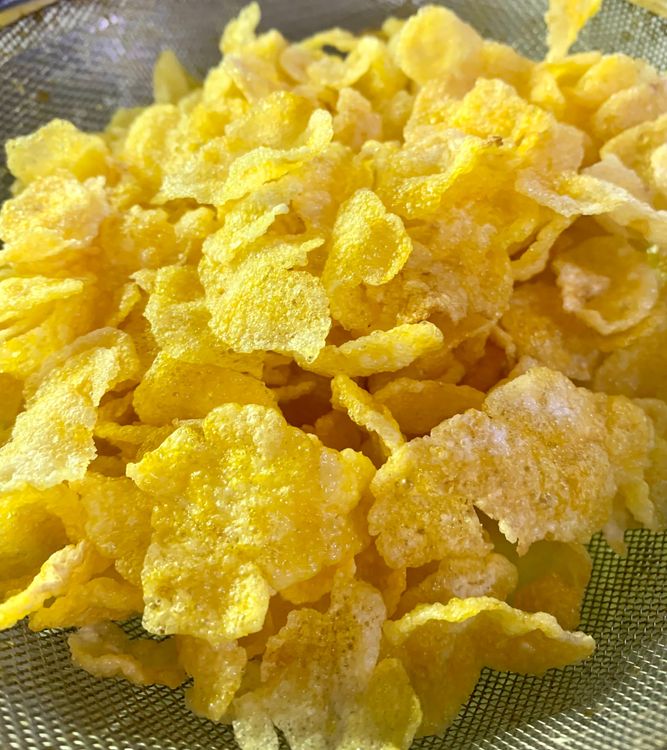 Step 2.1: Add the cornflakes to the hot oil in small portions and stir with a slotted spoon until they expand and are golden and crispy