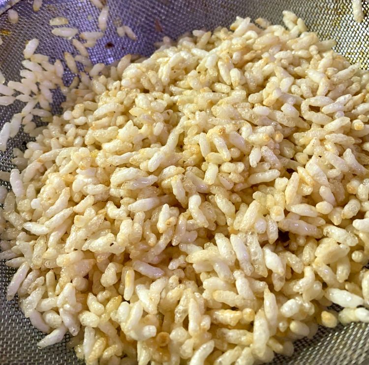 Step 2.2: Add puffed rice to the oil and fry for a few seconds before removing and placing them on the sieve