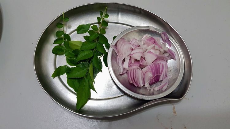 Step 2.2: Heat oil in a frying pan and add curry leaves, followed by the sliced onions