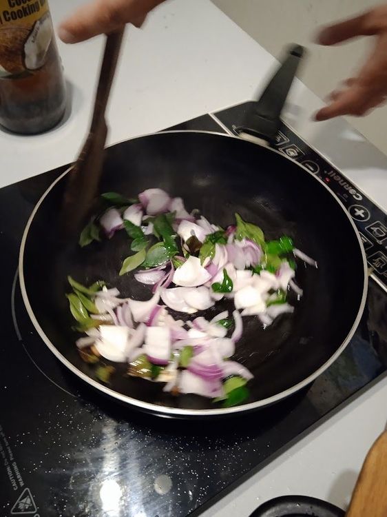Step 2.3: Heat oil in a frying pan and add curry leaves, followed by the sliced onions