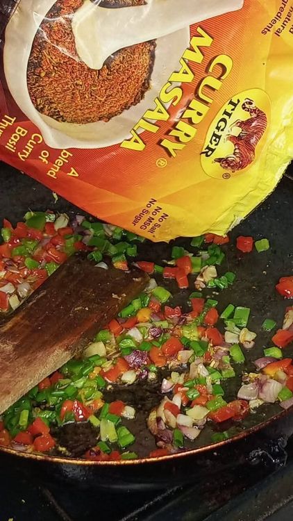 Step 2.2: Add the seasoning cube, stir, and then add the chopped bell peppers and spring onions