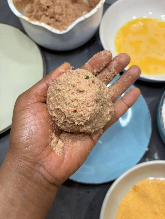 Step 3.2: Oil your palm, then gently wrap the eggs with the sausage mix
