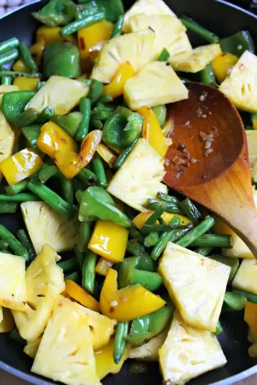 Step 1.1: Add the pineapple, cut into triangles, and stir fry for another 10 minutes until the vegetables are tender and the pineapple pieces are browning