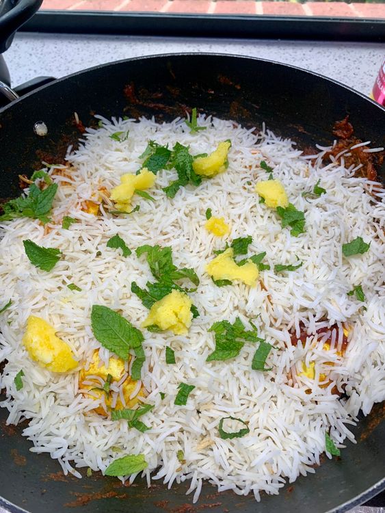 Step 4.1: Sprinkle kewra water, drizzle ghee, and add a few mint leaves
