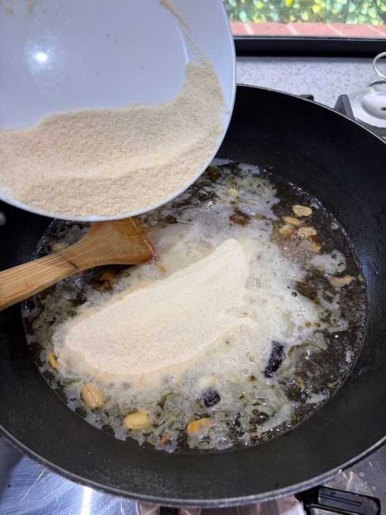Step 1.1: Slowly add the roasted rava while stirring continuously to avoid lumps