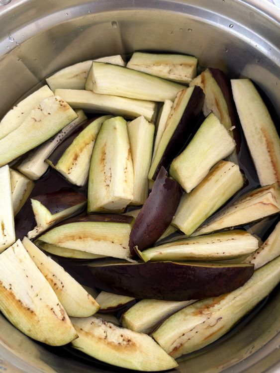 Step 1.1: Slice the brinjals lengthwise and immediately place them in a bowl of water to prevent discolouration