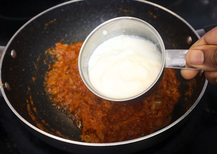 Step 2.1: Keeping the flame on low, add curd and stir continuously