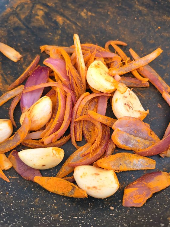 Step 1.2: In the same pan, dry roast the garlic cloves and sliced onion until lightly browned at the edges