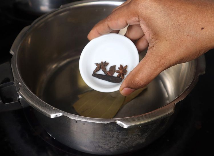 Step 1.2: Once the oil is hot, add bay leaf, cinnamon stick, cloves, stone flower, marati mogga, star anise, and shajeera