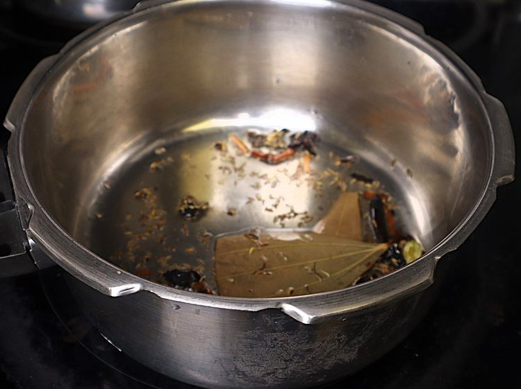 Step 1.6: Once the oil is hot, add bay leaf, cinnamon stick, cloves, stone flower, marati mogga, star anise, and shajeera