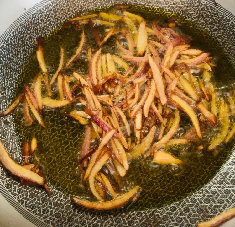 Step 1.2: Add the sliced onions and green chillies, stir-frying until the onion edges turn brown