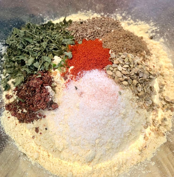 Step 1.1: Mix gram flour, green chillies, salt, red chilli powder, coriander seeds, garam masala, dry pomegranate seeds, carom seeds, garlic powder, dry fenugreek leaves, garlic powder, baking powder and baking soda in a large mixing bowl