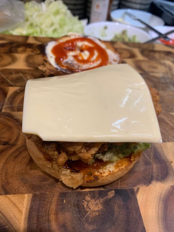 Step 4.2: Stack the burger bun with tomato sauce, avocado mix, fried chicken fillets, tomato slice, cheese slice and shredded lettuce