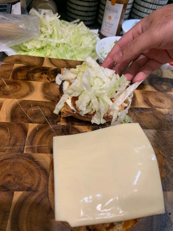 Step 4.3: Stack the burger bun with tomato sauce, avocado mix, fried chicken fillets, tomato slice, cheese slice and shredded lettuce