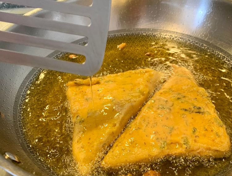 Step 1.1: Carefully lower the bread into the oil and let it fry for a minute