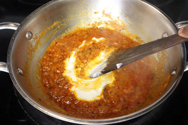 Step 2.2: Lower the flame, add curd, and cook until the oil separates again