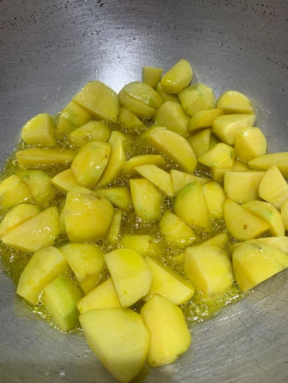 Step 1.1: Add a pinch of turmeric and the potatoes to the wok and stir-fry until they turn golden from the edges