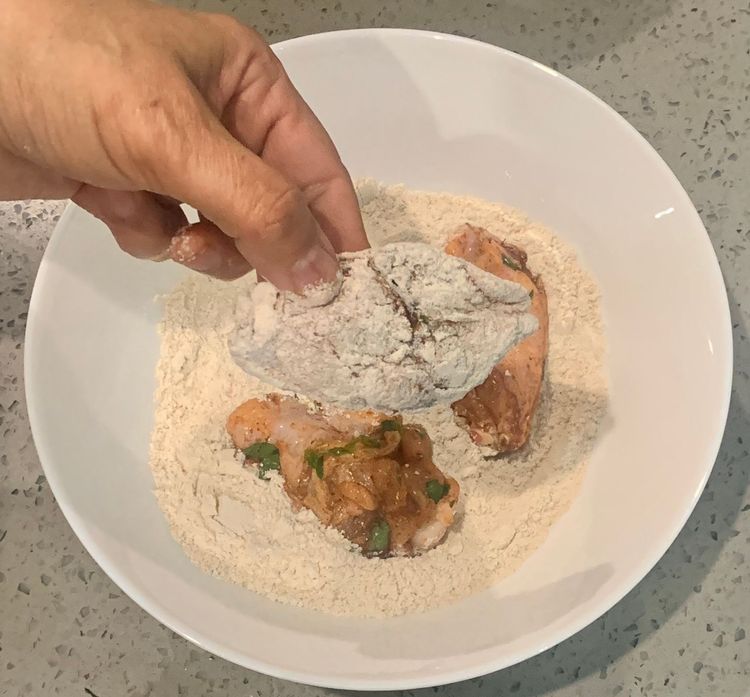 Step 1.1: Take each marinated chicken wing and coat it thoroughly with the flour mixture