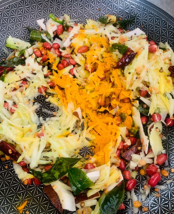 Step 1.1: Add the grated raw mango and turmeric powder to the pan