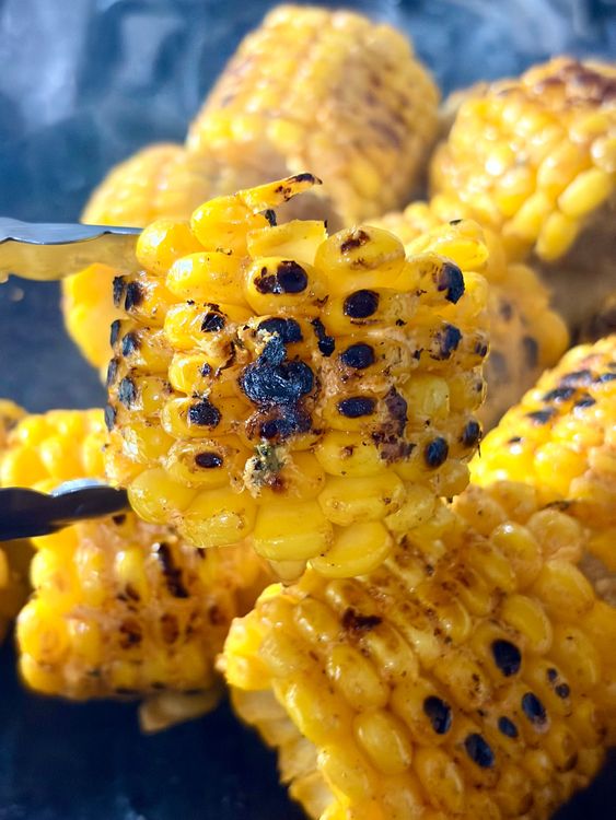 Step 3.2: Place the marinated corn cobs on the hot tawa or pan and grill, rotating frequently, until golden, lightly charred, and evenly cooked on all sides