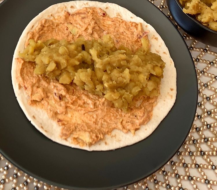 Step 3.1: Place a spoonful of warm mashed peas over the chutney in the centre of the wrap and roll it up