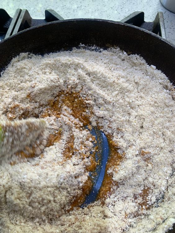 Step 2.1: Reduce the heat to low, then add the ground nut and makhana mixture to the jaggery syrup