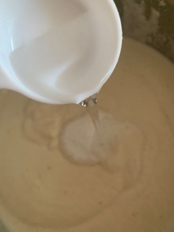 Step 1.1: Gradually add water to the mixture, stirring continuously, until a medium-thick, easy drop consistency idli batter forms without any lumps
