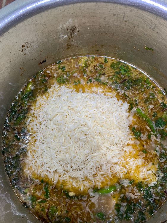 Step 4.1: Add the soaked and drained rice to the pot, gently mixing to combine with the yakhni and chicken