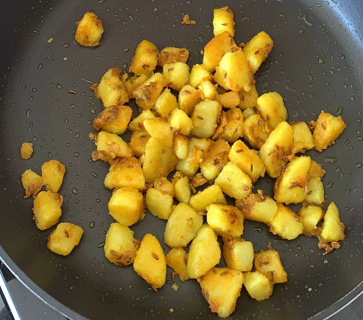 Step 1.2: Add turmeric and boiled potatoes into the pan and toss them well