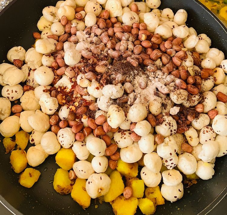 Step 1.1: Reduce heat, add the roasted Makhana, peanuts, rock salt, black salt, red chilli flakes and pomegranate powder