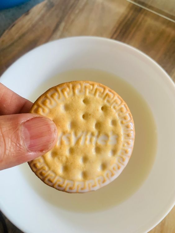Step 3.1: Dip each Marie biscuit briefly into the milk and arrange them in a single layer at the bottom of a flat serving dish or glass container