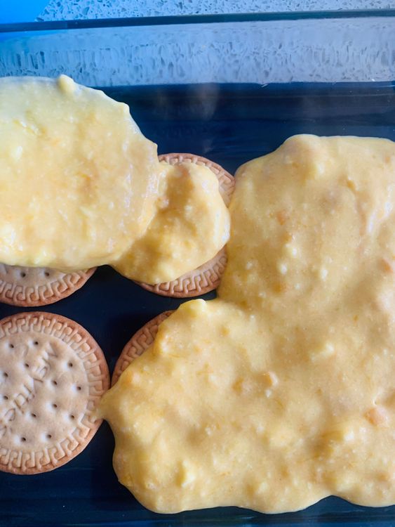 Step 3.1: Spread a thin layer of the mango cream mixture evenly over the biscuit layer