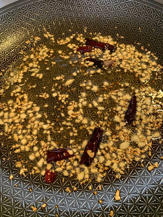 Step 3.1: Toss in dry red chillies and chopped garlic, sautéing until golden