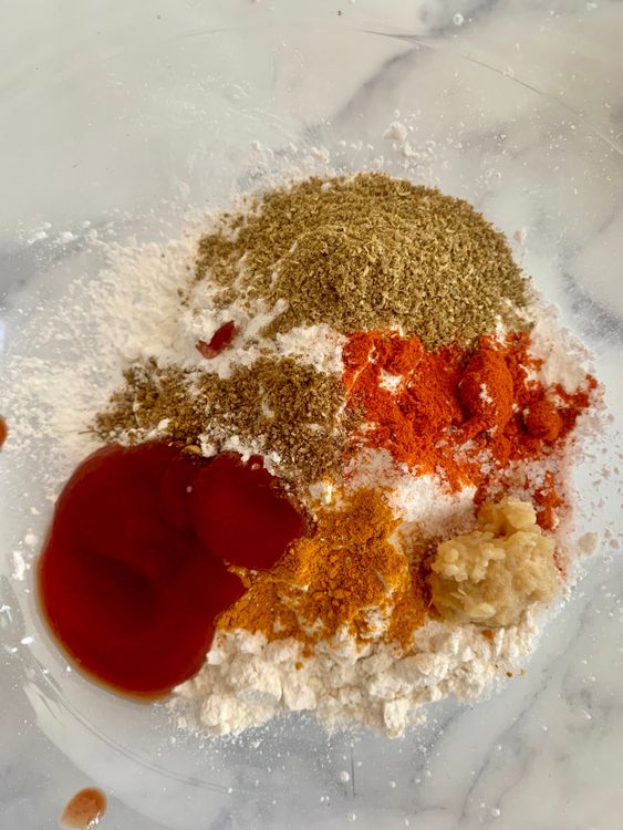 Step 2.1: In a mixing bowl, combine all-purpose flour, cornflour, ginger-garlic paste, red chilli powder, turmeric powder, coriander powder, garam masala, salt, and tomato ketchup