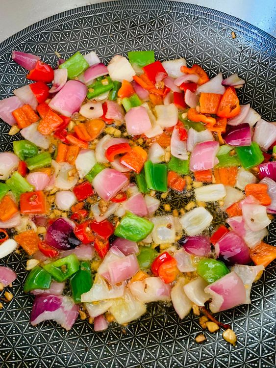 Step 3.1: Add cubed onions and capsicum, stir-frying on high heat for 1-2 minutes