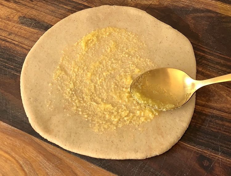 Step 2.1: Brush ghee on the rolled dough, place stuffing in the centre, fold the edges to cover, and gently roll into a circular shape