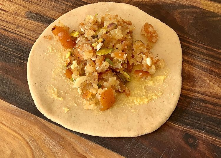Step 2.2: Brush ghee on the rolled dough, place stuffing in the centre, fold the edges to cover, and gently roll into a circular shape