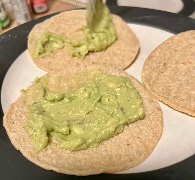 Step 1.1: When you’re ready to serve, take a corn tortilla and spread it with some of the avocado spread