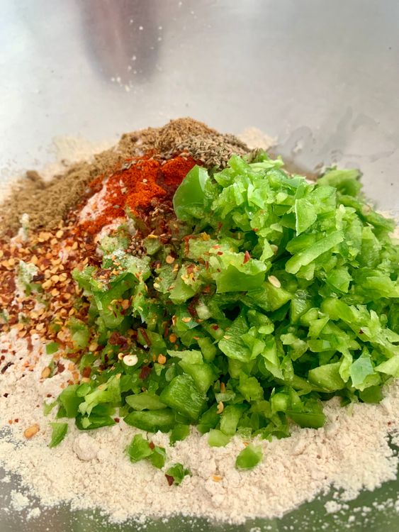 Step 1.1: In a large mixing bowl, combine the whole wheat flour, chopped capsicum, salt, Kashmiri red pepper powder, cumin powder, garam masala, carom seeds, red chilli flakes and 2 tbsp of oil