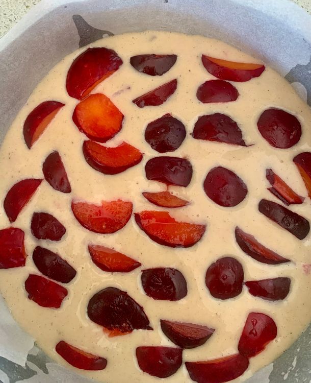 Step 1.1: Pour the batter into the prepared cake pan and decorate the top with sliced plums
