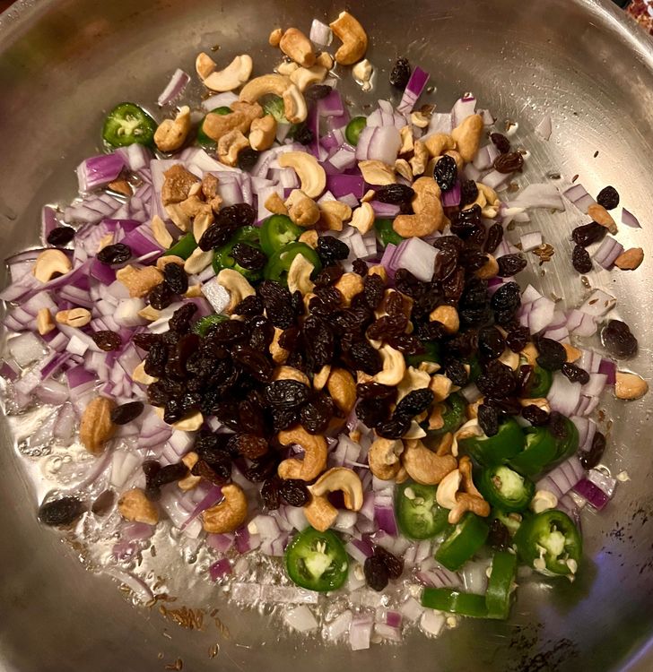 Step 2.1: Next, add the red onion, serrano peppers, cashews, and raisins