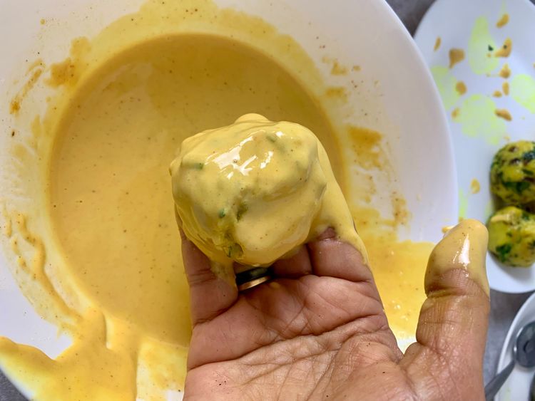 Step 3.1: Dip each potato ball into the batter, ensuring it's evenly coated, and gently slide it into the hot oil