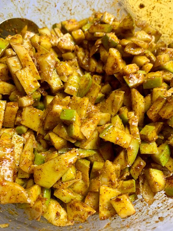 Step 4.1: Toss the dried mango pieces into the spice mix, coating them evenly